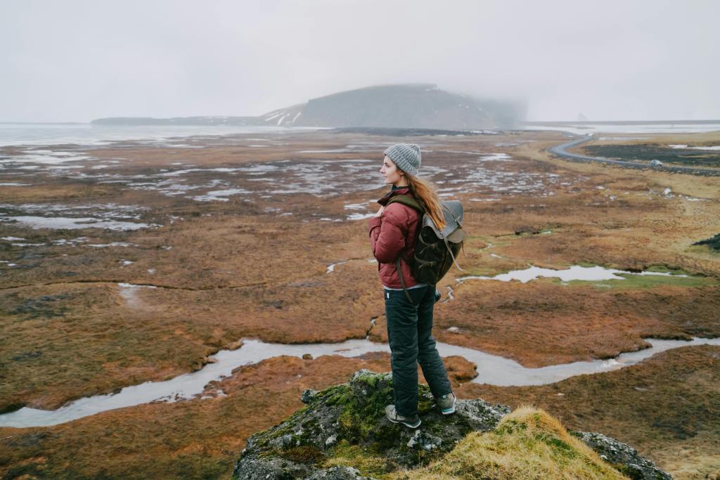 Vrouw staat op een berg met uitzicht in IJsland