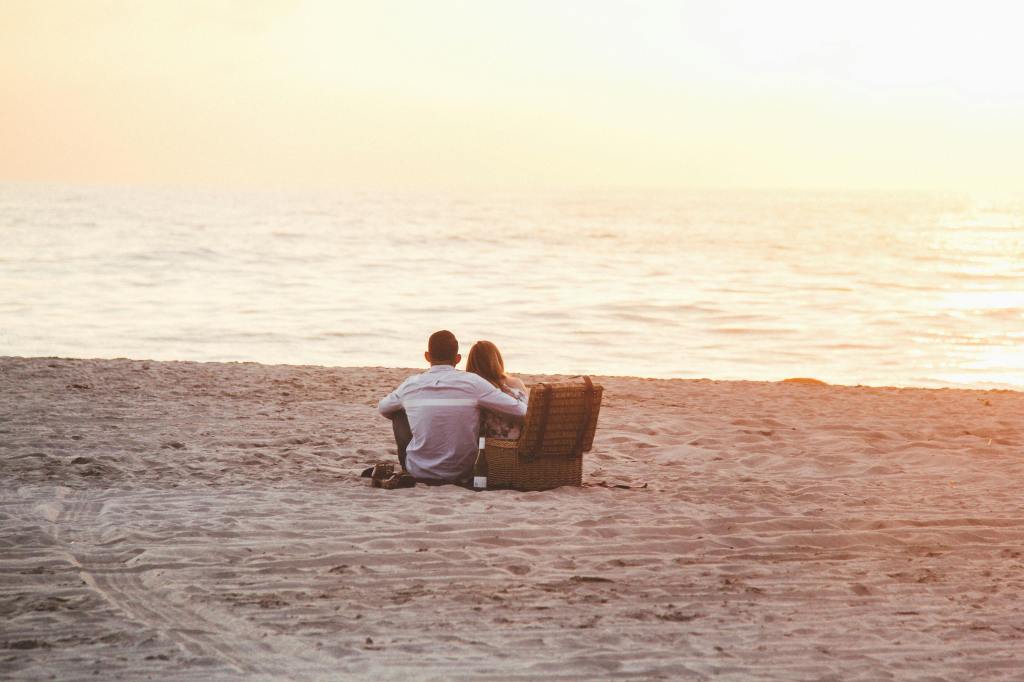 Koppel zit samen op het strand met zonsondergang