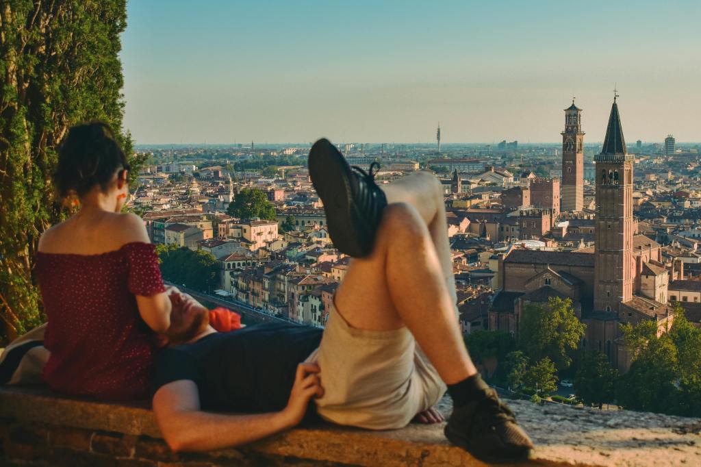 Koppel zit op muurtje met uitzicht op een stad in Italië