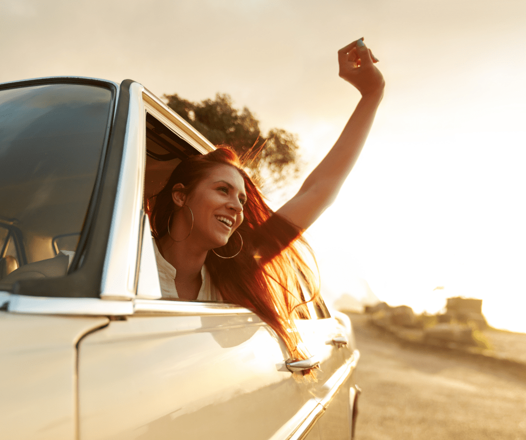 Vrouw in auto met arm uit het raam op roadtrip